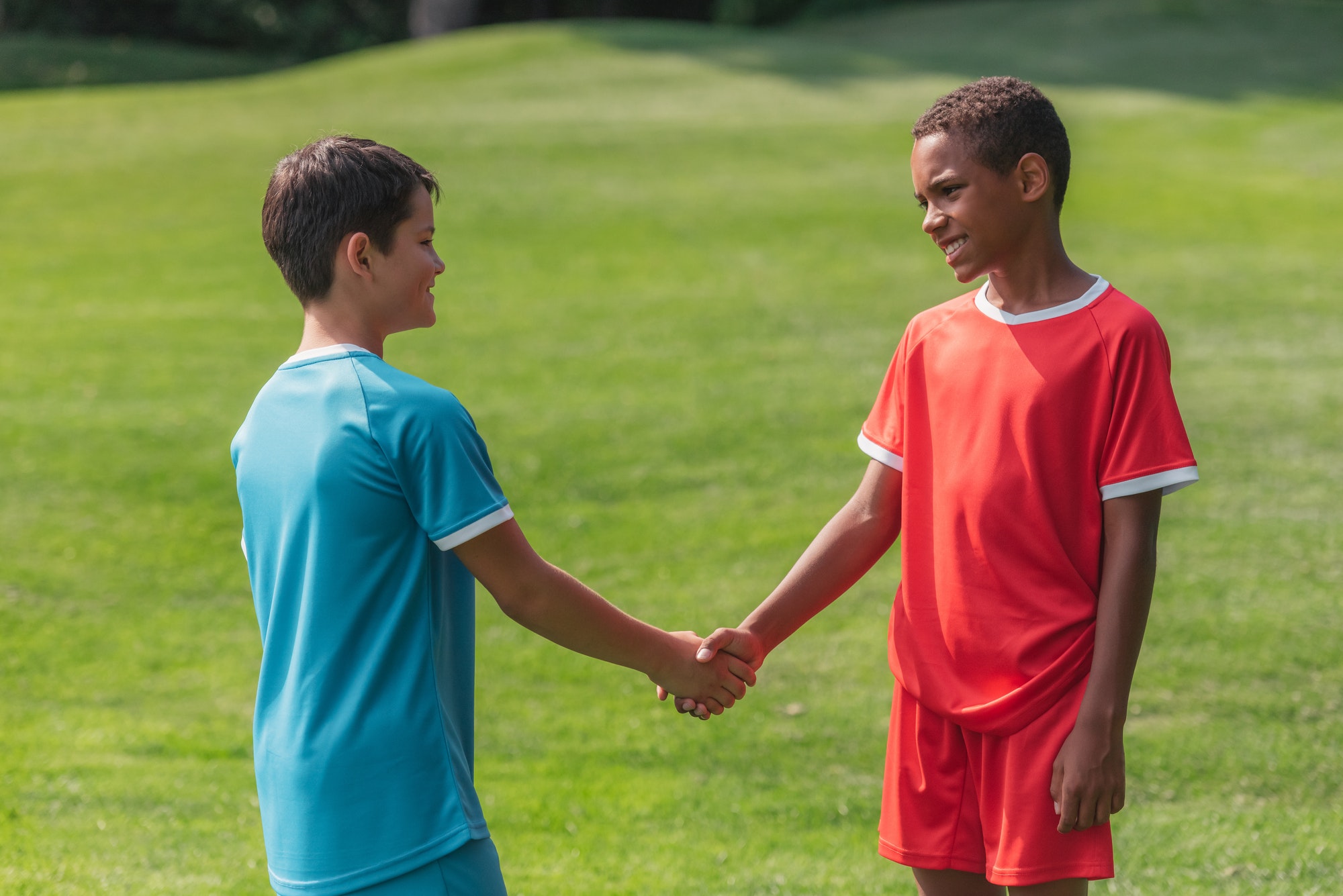 happy multicultural kids shaking hands outside